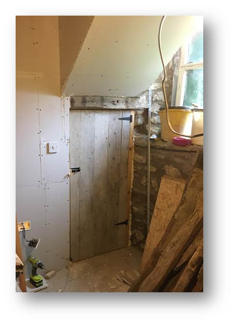 image of an under-stairs cupboard door constructed with reclaimed floorboards